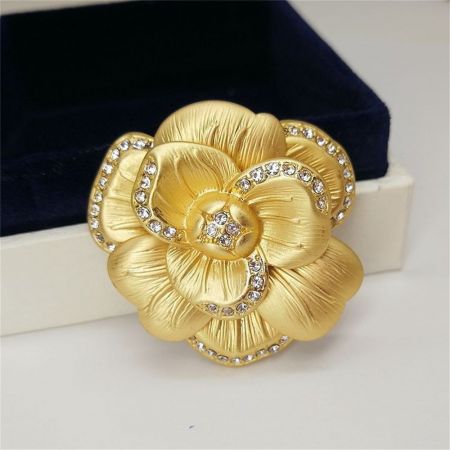 ヴィンテージの金色の花のブローチの斜めショットで、繊細な花びらと宝石の中心を強調しています。
