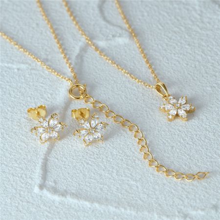 Une vue en angle de l'ensemble de bijoux flocon de neige en or sur un fond blanc.