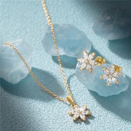 L'ensemble de bijoux flocon de neige en finition or luxueuse, mettant en valeur le design complexe et les pierres précieuses claires.