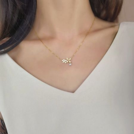 Collier en argent sterling 925 en gros avec pendentif en forme de feuille de trèfle en zircon et perle. - Gros plan sur un collier en argent sterling 925 avec une finition dorée, présentant un pendentif en forme de feuille de trèfle serti de zircon et une perle centrale, représentant l'ensemble en gros.