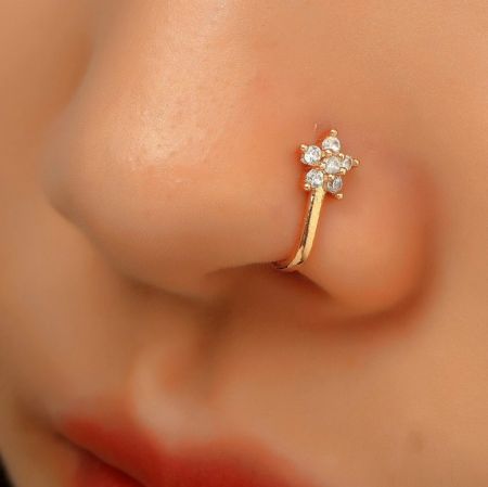 Primo piano di un fermaglio per naso in argento sterling placcato oro a forma di fiore adornato con scintillanti gemme in zirconia cubica.