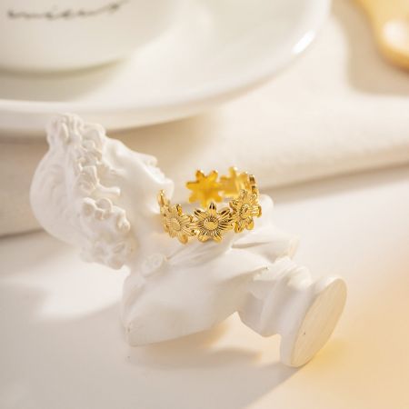Photo artistique du produit de la bague en or en forme de tournesol affichée sur une statue décorative.