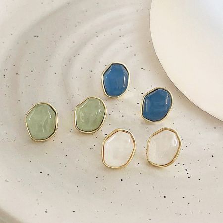 An assortment of the 14K gold plated resin earrings on a decorative plate.