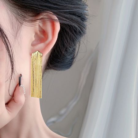 Modello che indossa l'orecchino a frangia lunga in oro esagerato per mostrare la sua lunghezza e stile.