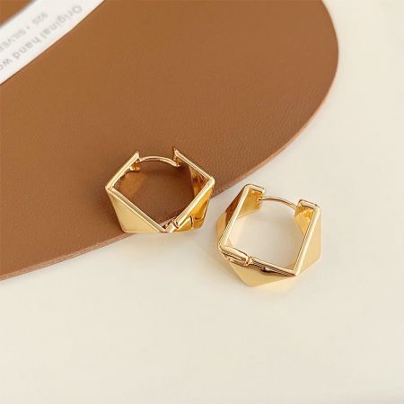 金メッキの幾何学的フープイヤリングの詳細なビューで、磨かれた仕上げを示しています。