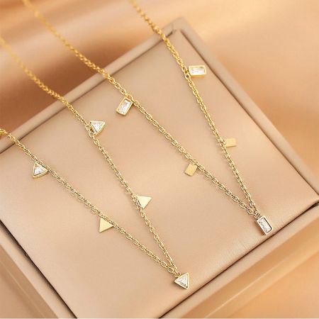 Tre distinte collane con charm geometrici della collezione esposte insieme.