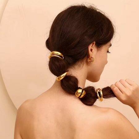 Primer plano del accesorio para el cabello en forma de labios dorados asegurando una coleta de mujer.