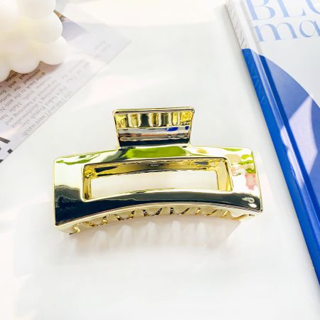 El agarre de pelo metálico dorado mostrando su diseño cuadrado hueco.