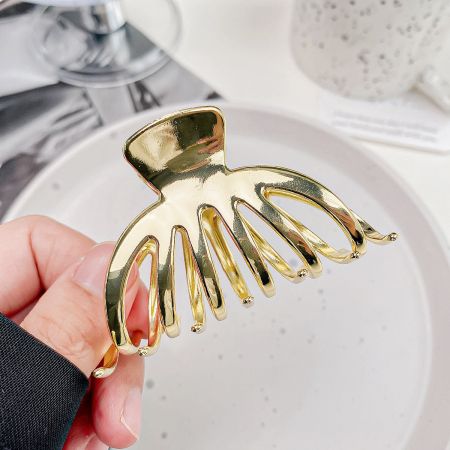 Clips para el cabello antideslizantes en forma de calabaza de metal para mujeres. - Una toma de producto en primer plano de un elegante clip para el cabello de metal dorado en una forma única de calabaza, exhibido sobre un fondo blanco limpio.