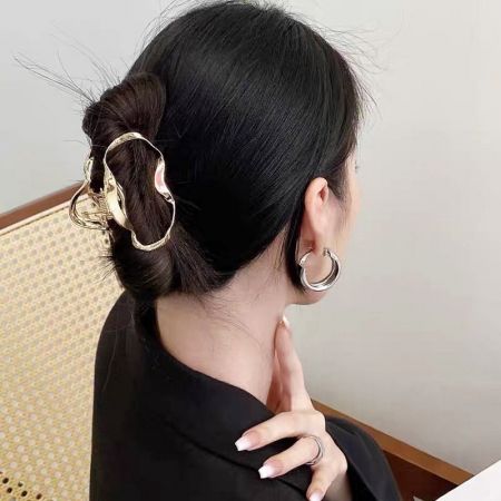 A woman with her hair in a bun, secured by a gold cloud-shaped wave hair clip.