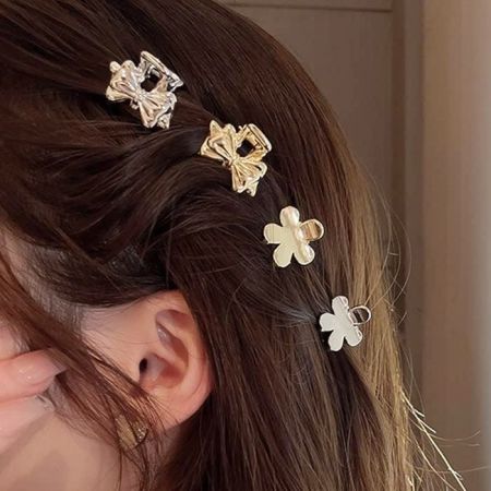 Close-up of gold bow and flower shaped mini hair clips.