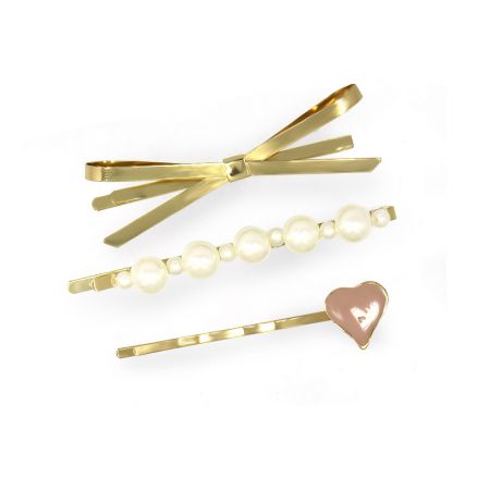 Primer plano de tres accesorios para el cabello dorados: un clip en forma de lazo, un clip adornado con perlas y un clip decorado con un corazón.