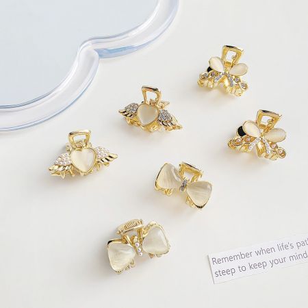 Assortment of delicate mini hair clips in gold, shaped like hearts and bows, embellished with pearls.
