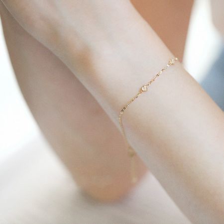 Un modelo que lleva la delicada pulsera de charm en forma de corazón de oro para mostrar su ajuste y estilo.