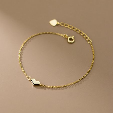 Een schone productfoto van de gouden hartbedelarmband tegen een witte achtergrond.