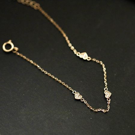 Toma detallada en estudio de la pulsera de charm en forma de corazón de oro, mostrando su fina artesanía.