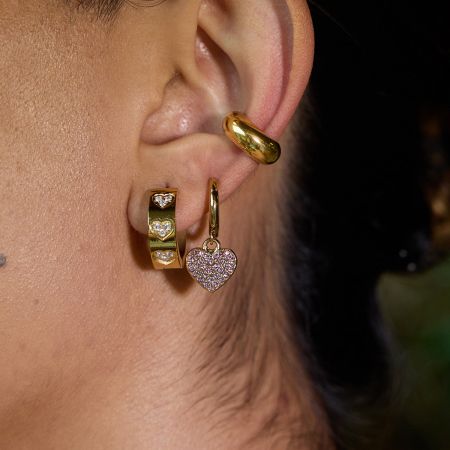 A model wearing the gold Heart Zircon Hoop Earring while holding the silver version, demonstrating the versatility of the set.