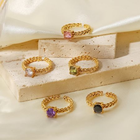 Coleção de anéis dourados com pedras preciosas em forma de coração em várias cores.