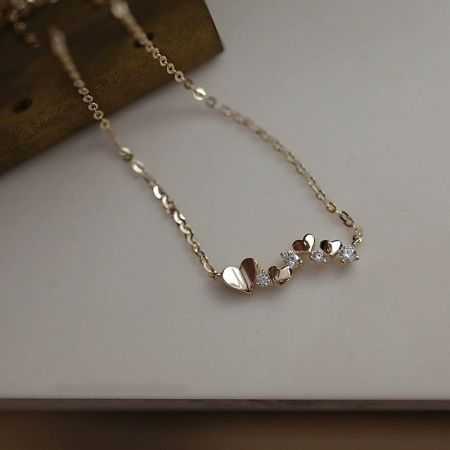 Otro ángulo del collar de corazón dorado que resalta el brillante circonio cúbico.