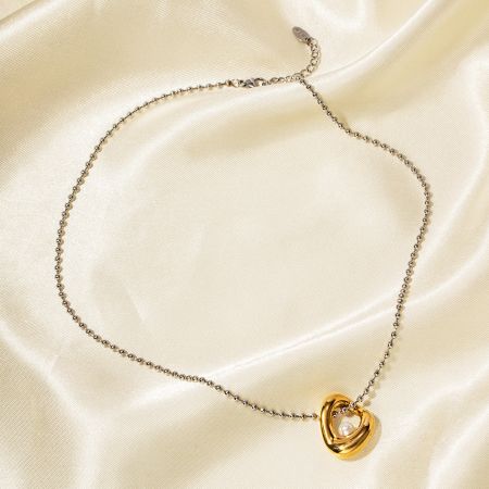 Collar de oro con un colgante de corazones entrelazados con una perla.