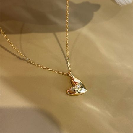 El collar con colgante de corazón de oro de 18K exhibido sobre un fondo neutro.