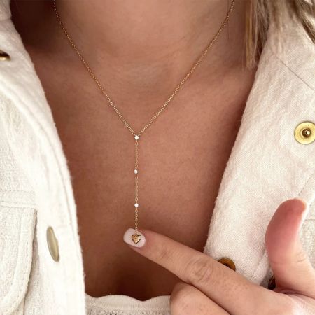 Modelo usando el collar con charm en forma de corazón Y de acabado dorado.