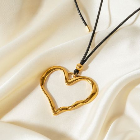 Collar de cuero con colgante de corazón hueco de acero inoxidable (set de 5) - Un primer plano del colgante de corazón hueco de acero inoxidable dorado en un collar de cuero negro, parte de un set de 5.