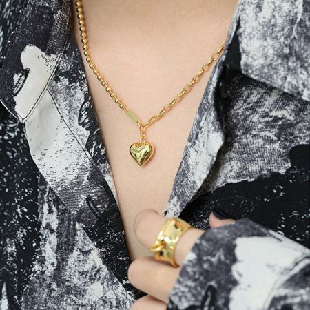 Le collier en cœur doré épais associé à une bague assortie, démontrant un look complet.