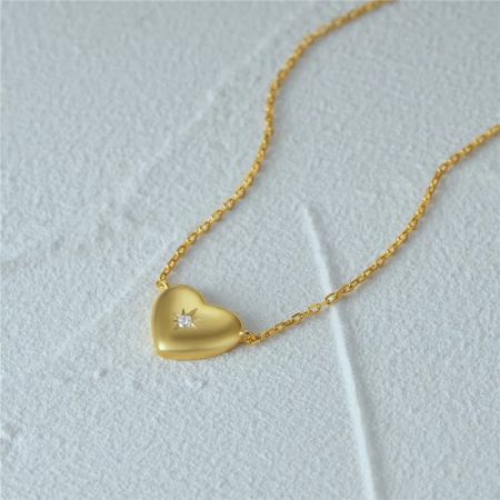 Primo piano della collana con pendente a cuore d'oro con una pietra di zirconia centrale.