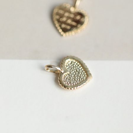 Dos colgantes de corazón dorado que muestran su superficie texturizada y bordes ondulados, representando la calidad del conjunto.
