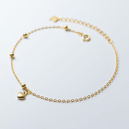 925 Zilver 18K Gouden Ronde Kraal Mini Hart Bedelarmband - Een delicate 925 sterling zilveren armband verguld met 18K goud, met een mini hart bedel en ronde kralen op een witte achtergrond.