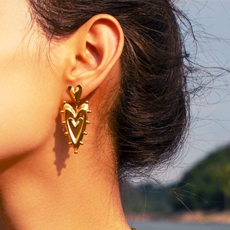 Model wearing the gold double-heart drop earrings, showcasing their elegant drape.