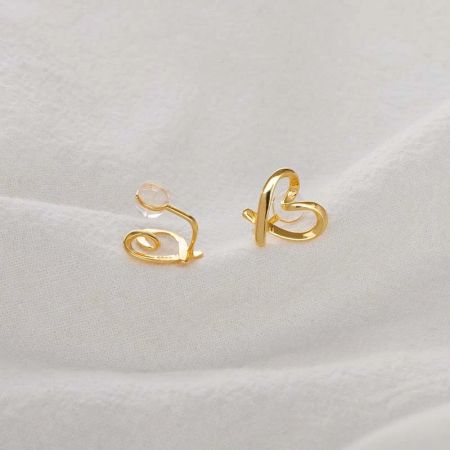 Vista dettagliata dell'orecchino a clip a forma di cuore in oro con un design vorticoso.