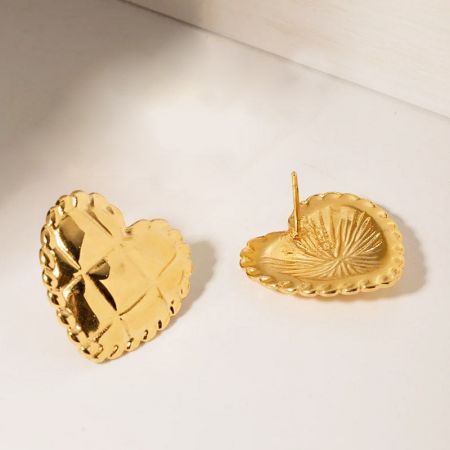 Toma detallada del diseño intrincado y los bordes de cuentas de los pendientes de corazón dorados.