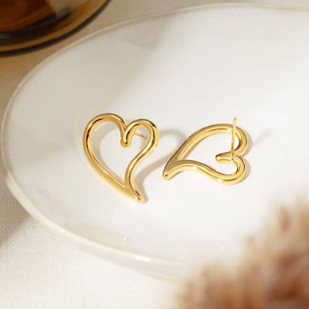 Een close-up van de gouden holle hartstud oorbellen, die hun gladde textuur en vorm benadrukt.