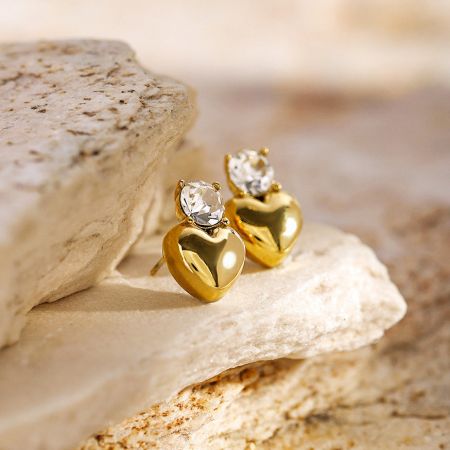 Otro ángulo de los pendientes en forma de corazón dorado con piedras preciosas claras.