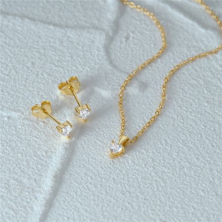 Prise en angle de l'ensemble de bijoux en cœur doré mettant en valeur les cristaux de zircon.