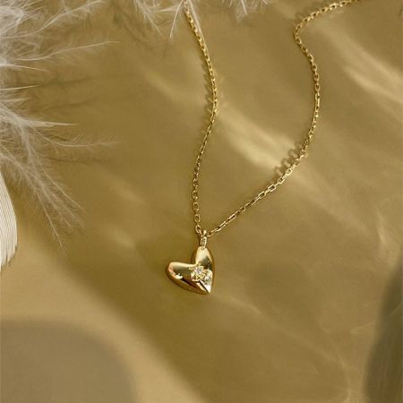 Vista detallada del diseño de estallido en el colgante en forma de corazón dorado.