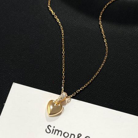 Close-up of a delicate gold heart-shaped necklace pendant on a chain, a popular item in the wholesale heart jewelry collection.