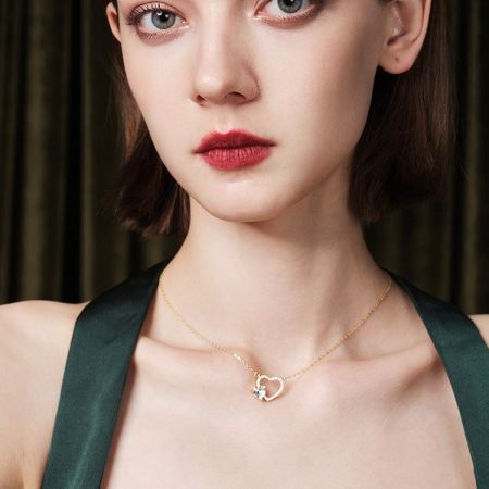 Modelo usando el collar de corazón hueco de oro con circonio, mostrando su longitud y estilo.