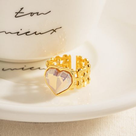 Detalhe da faixa larga do anel de pedra coração dourado.