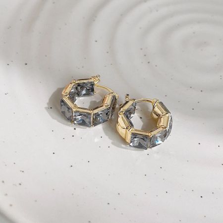 六角形のクリアな宝石を特徴とする金のイヤリングのペア。