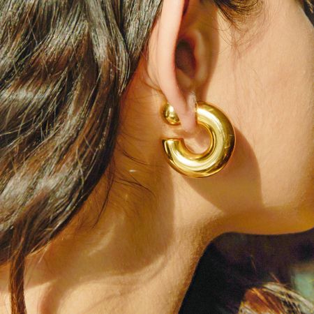 Close-up of a model wearing the chunky gold ball stud earring.