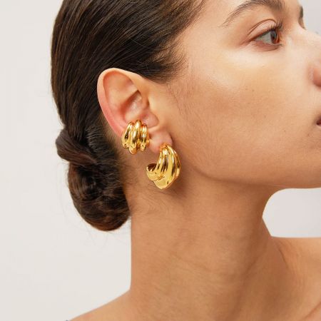 A model elegantly displays the gold chunky hoop earrings, complementing her look.