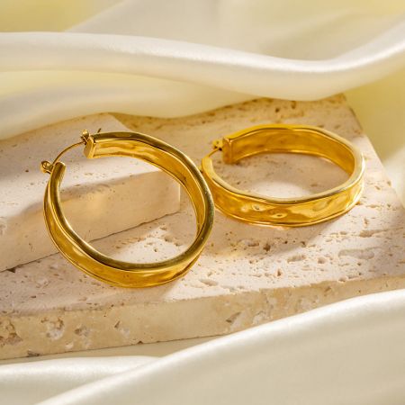 Vooraanzicht van de roestvrijstalen geslagen gouden hoepel oorbellen.