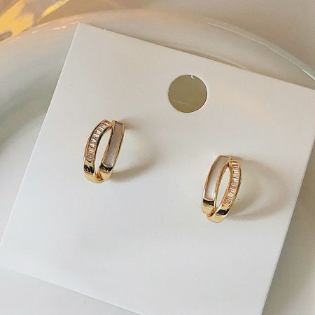 Close-up product view of the 18K gold geometric cross earrings on a display card.