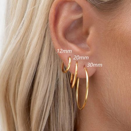 Un modello che mostra le diverse dimensioni degli orecchini a cerchio in oro per un senso di scala.