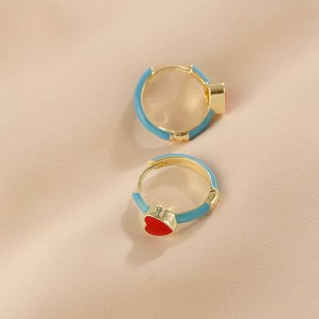 Une variation de la boucle d'oreille huggie avec un pendentif en forme de cœur rouge.