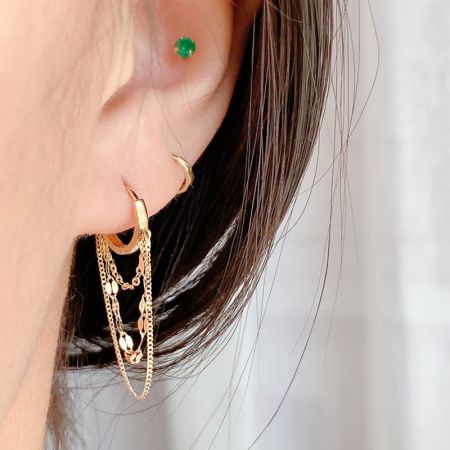Orecchini a cerchio huggie a catene multilivello in argento sterling 925 (set di 5) - Un set di cinque orecchini a cerchio e huggie in argento sterling 925 multilivello con catene pendenti, presentati in una finitura dorata radiosa.
