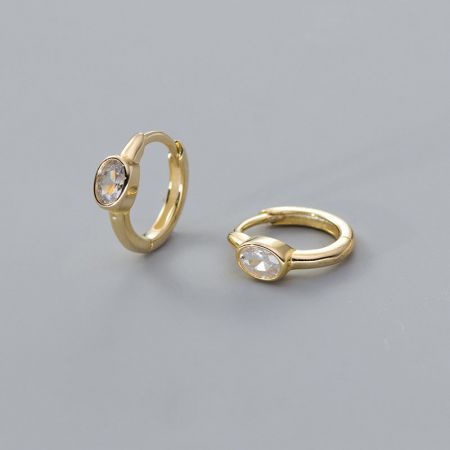 Elegant gold-plated huggie hoop earrings with brilliant clear oval gemstones.